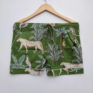 May include: Green cotton shorts with a white trim. The shorts feature a jungle print with leopards, birds, and palm trees.