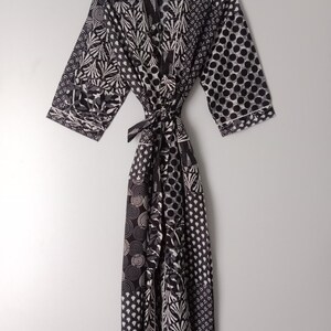May include: Black and white patterned robe with a long, flowing design. The robe has a sash tie at the waist and three-quarter length sleeves.