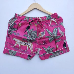 Può includere: Shorts di cotone rosa con bordino bianco e stampa di animali della giungla con leopardi, zebre, tucani e fenicotteri.