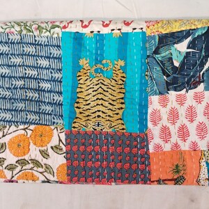 May include: A patchwork textile featuring a tiger design and various patterns. The quilt showcases a vibrant mix of colors, including blue, orange, red, and white. The design includes floral, leaf, and geometric patterns.