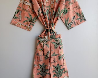 Könnte beinhalten: Eine pfirsichfarbene Baumwollrobe mit einem Dschungelprint mit Leoparden, Zebras, Vögeln und Palmen. Die Robe hat einen Bindegürtel und eine Tasche.