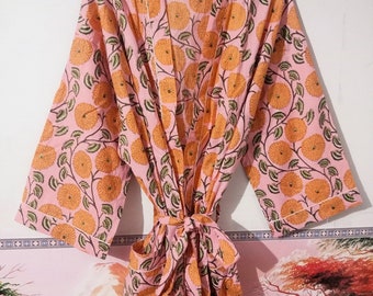 Könnte beinhalten: Eine rosa Baumwollrobe mit einem Blumendruck mit orangefarbenen Blüten und grünen Blättern. Die Robe hat einen Bindegürtel und lange Ärmel.