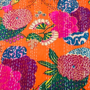 Peut inclure: Un tissu orange vif avec un motif floral. Les fleurs sont roses, violettes, bleues et vertes. Le tissu est matelass&eacute; avec du fil blanc.