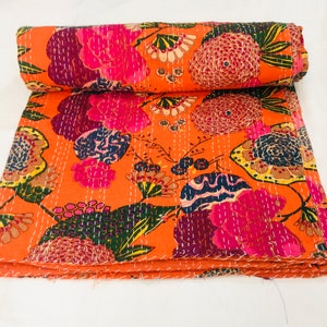 Peut inclure: Une courtepointe kantha orange vif avec un motif floral dans des tons de rose, violet, vert et jaune. La courtepointe est pli&eacute;e en trois et a un fond blanc.