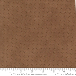 May include: A square of brown fabric with a repeating pattern of small, dark brown arrow-like shapes. The fabric has a subtle texture and a ruler is visible along the bottom edge.