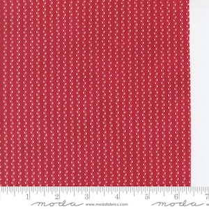 May include: Red fabric with a repeating pattern of small, white leaf-like shapes arranged in vertical rows. The fabric has a ruler along the bottom edge, with the word "moda" printed on it.