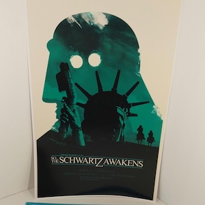 May include: A green and black poster with a silhouette of Darth Vader's head. The Statue of Liberty is visible in the background. The text "Spaceballs: So the Schwartz Awakens" is at the bottom of the poster.