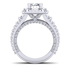 May include: A silver engagement ring with a large center diamond surrounded by smaller diamonds. The ring has a double band with diamonds set in a pave setting.