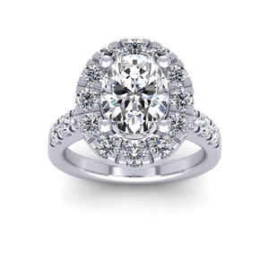 Puede incluir: Un anillo de compromiso de plata con un diamante central de forma ovalada rodeado por un halo de diamantes más pequeños. La banda también está engastada con diamantes más pequeños.