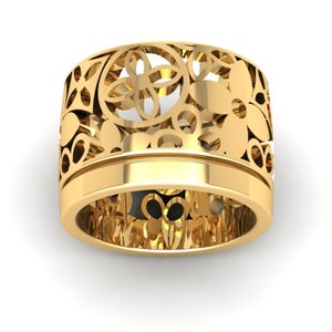 May include: A gold filigree ring with a floral design. The ring is wide and has a delicate, intricate pattern.