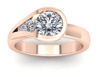 May include: A rose gold ring featuring a large, round, clear gemstone in a bezel setting, with three smaller gemstones set in a curved channel. The ring has a smooth, polished band and a modern, elegant design.