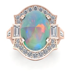 Puede incluir: Un anillo de oro rosa con una gran piedra de ópalo ovalada rodeada por un halo de diamantes más pequeños. El anillo tiene un diseño decorativo con diamantes baguette a cada lado.