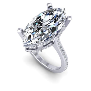 May include: A silver ring with a large marquise-shaped diamond set in a prong setting. The diamond is surrounded by a halo of smaller diamonds. The band of the ring is also set with smaller diamonds.