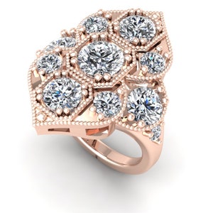 May include: A rose gold ring with a cluster of round diamonds set in a geometric design. The ring has a delicate, vintage-inspired look.