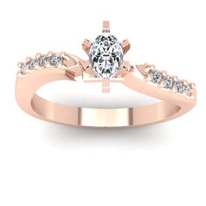 May include: A rose gold engagement ring with a single oval-shaped diamond and smaller diamonds set in a pave setting along the band.