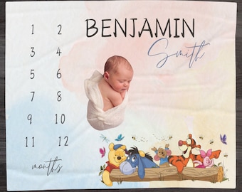 May include: A Winnie the Pooh themed baby milestone blanket with a watercolor background. The blanket has a chart for tracking a baby's growth from 1 to 12 months. The blanket also features a photo of a baby and the name "Benjamin Smith" written in cursive.