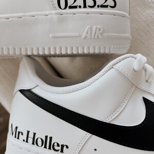May include: White sneakers with black accents. The shoes feature the text "02.15.25" on the heel and "Mr. Holler" on the side. The word "AIR" is visible on the sole.