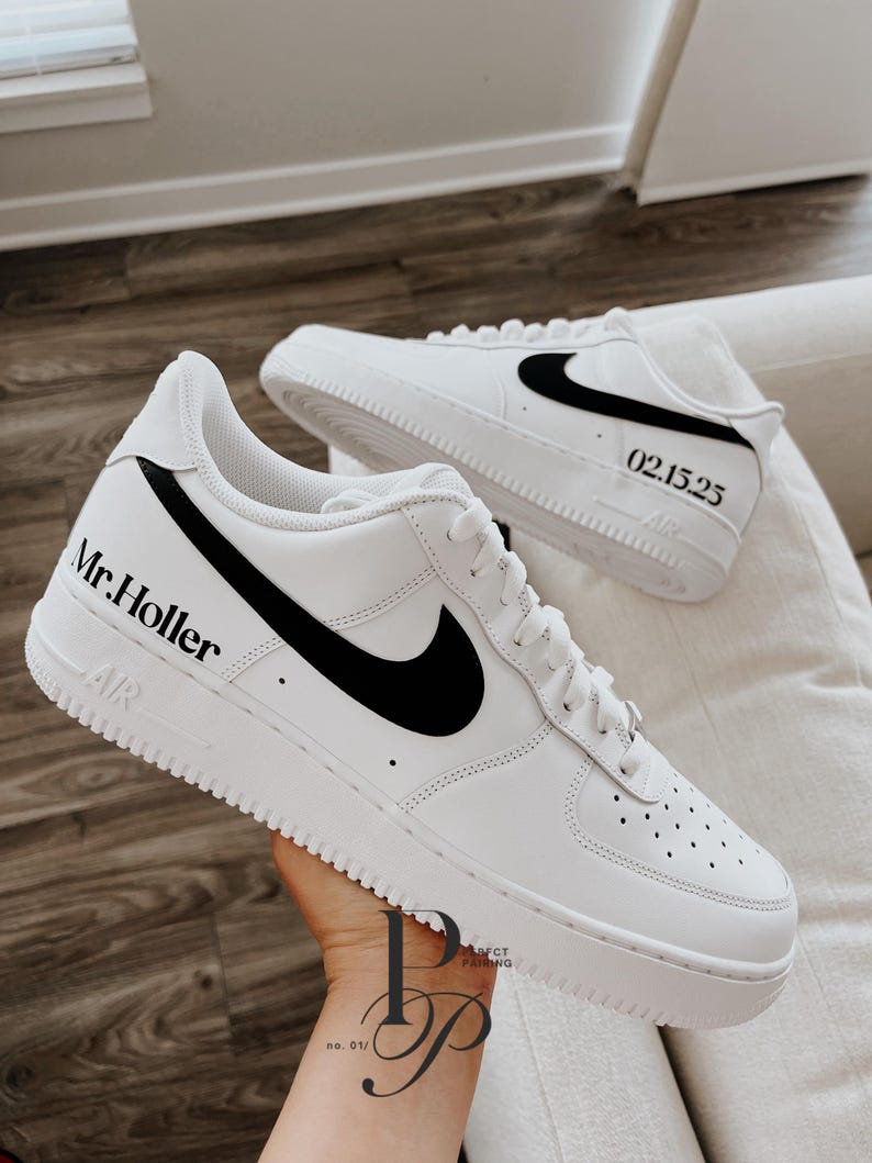 May include: White sneakers with black accents, featuring the text "Mr. Holler" and the date "02.15.25". The shoes have a classic design with a black swoosh logo on the side.