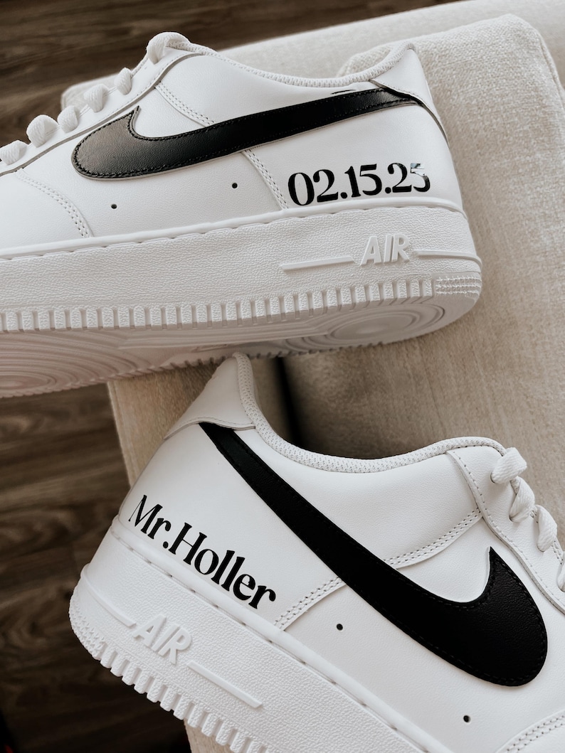 May include: White sneakers with black swooshes and soles. The text "02.15.25" is printed on the side of one shoe, and "Mr. Holler" is printed on the side of the other shoe. The word "AIR" is printed on the sole.