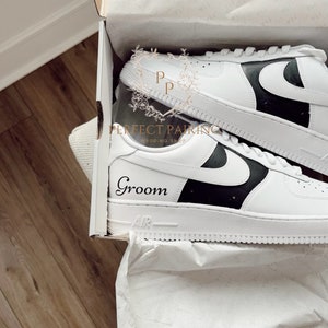 May include: White trainers with a black swoosh and a black panel on the side. The trainers are in a white box with tissue paper. The word "Groom" is written on the side of the trainer.