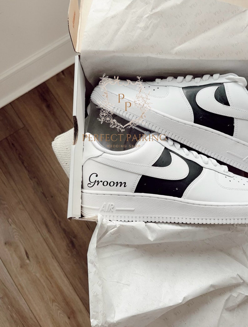 May include: White trainers with a black swoosh and a black panel on the side. The trainers are in a white box with tissue paper. The word "Groom" is written on the side of the trainer.
