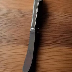 May include: A silver butter knife with a rounded handle.