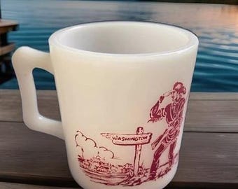May include: White ceramic mug with a red illustration of a person pointing to a sign that reads "WASHINGTON".