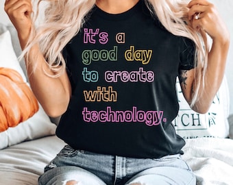 May include: A black t-shirt with the text "it's a good day to create with technology." in rainbow colors.