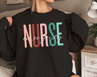 May include: Black sweatshirt with the word "NURSE" in colorful letters and the word "emergency" written in white script below.
