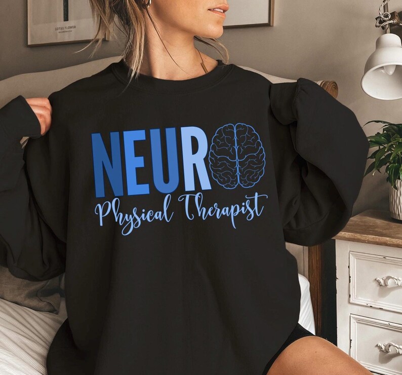 Puede incluir: Sudadera negra con las palabras "NEURO Physical Therapist" en azul. Un gr&aacute;fico de cerebro azul est&aacute; a la derecha de la palabra "NEURO". El texto est&aacute; en una fuente sans-serif, con "Physical Therapist" en una fuente cursiva.