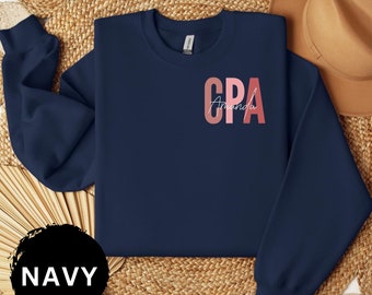 May include: Navy blue sweatshirt with a pink and red "CPA" graphic and the name "Amanda" written in white below.