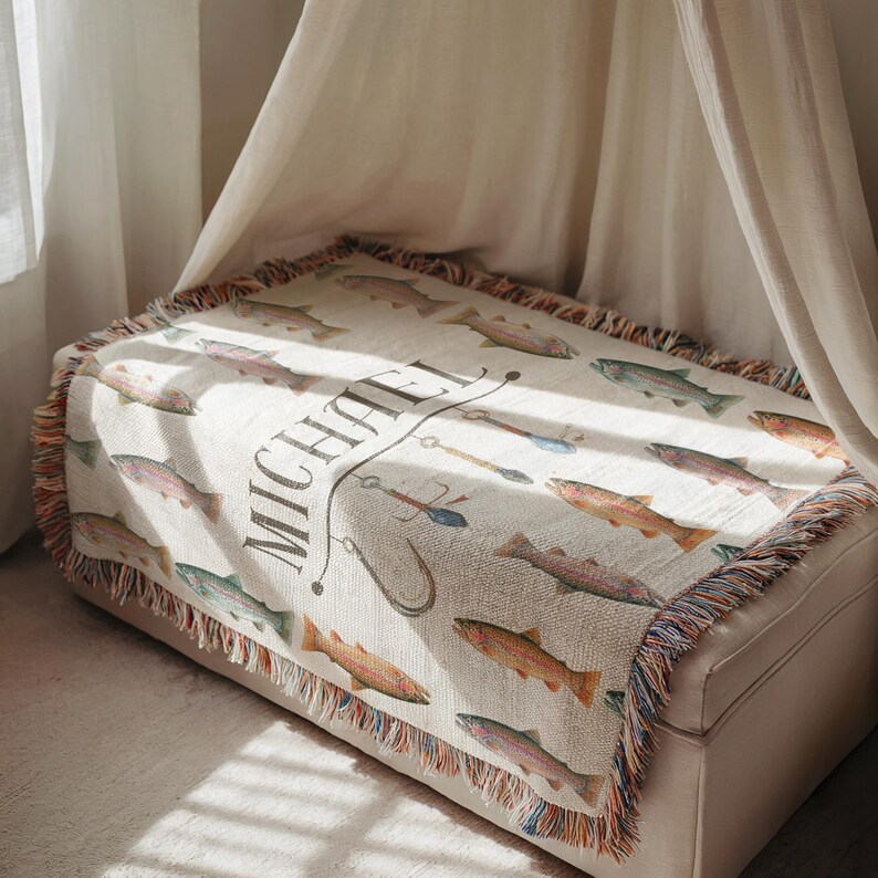 May include: Cream-colored throw blanket featuring a repeating pattern of colorful fish. The blanket has a fringed edge with a mix of colors. The name "MICHAEL" is printed in a decorative font, along with fishing-related illustrations.