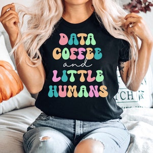 May include: A black t-shirt with the text "DATA COFFEE and LITTLE HUMANS" in colorful, retro-style lettering.