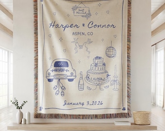May include: Cream-colored woven throw blanket with a blue line drawing of a car, wedding cake, and disco ball. The text "Just Married", "Harper & Connor Aspen, CO", and "January 3, 2026" are also in blue.