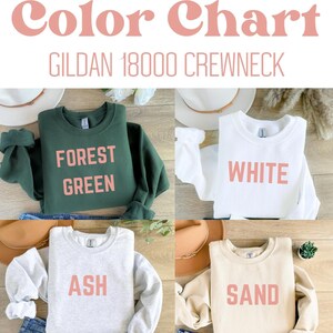 May include: A color chart featuring four Gildan 18000 crewneck sweatshirts. The sweatshirts are forest green, white, ash, and sand. Each sweatshirt displays its color name in a pink font. The image includes hats and jeans.