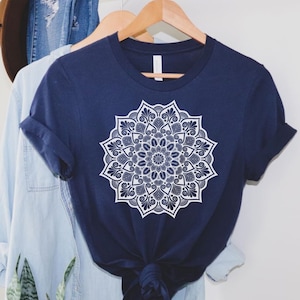 May include: A navy blue t-shirt with a white mandala design. The mandala is intricate and detailed, with a floral pattern.
