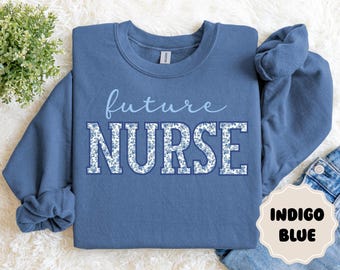 Könnte beinhalten: Indigoblaues Sweatshirt mit dem Aufdruck "future NURSE". Das Wort "NURSE" ist in großen Blockbuchstaben mit floralem Muster gehalten. Das Sweatshirt hat einen Rundhalsausschnitt und lange Ärmel.