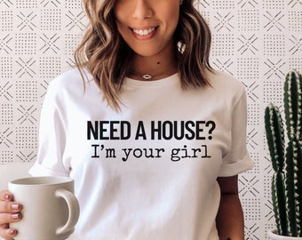 May include: White t-shirt with black text that reads "NEED A HOUSE? I'm your girl."