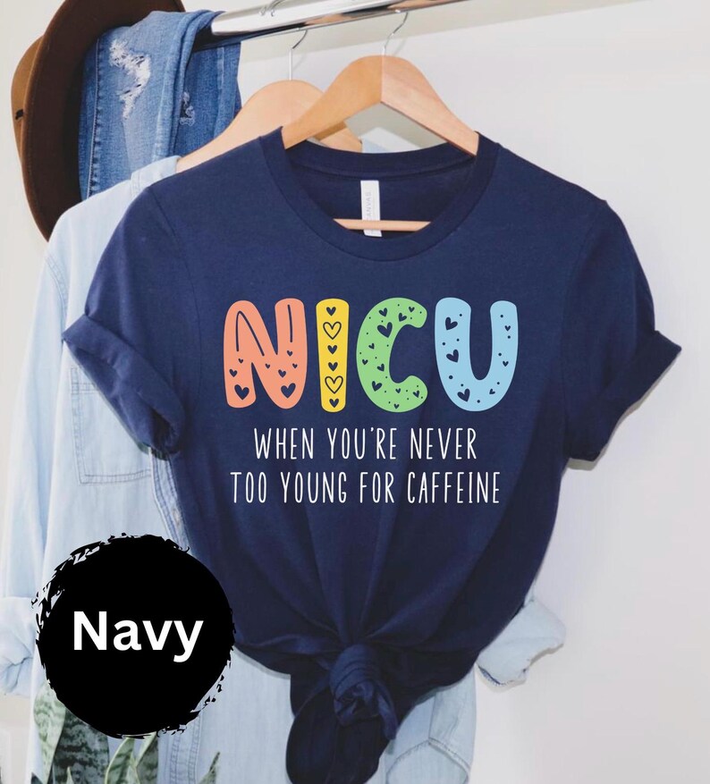 May include: Navy blue t-shirt with a colorful "NICU" graphic and the text "When you're never too young for caffeine".
