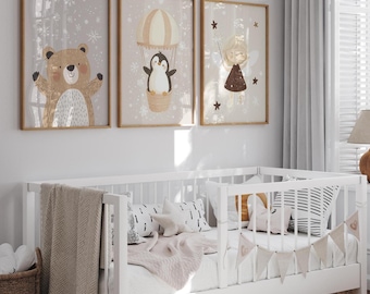 May include: Three framed illustrations of a brown bear, a penguin in a hot air balloon, and a fairy with stars. The illustrations are on a white wall above a white crib with a white blanket and pillows.