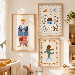 K&ouml;nnte beinhalten: Drei gerahmte Wandbilder mit verspielten Illustrationen. Eines zeigt einen K&ouml;nig mit Krone und Stab, ein weiteres ein Haus mit Pferden und Blumen mit der Aufschrift "HOME IS HERE" und das dritte einen B&auml;ren auf einem blauen Podest.