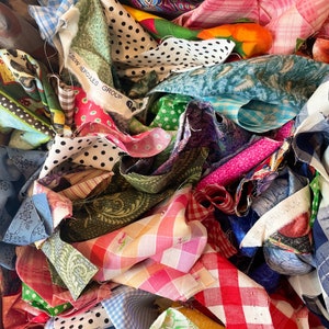 May include: A pile of colorful fabric scraps in various patterns, including polka dots, plaid, and floral prints. The scraps are arranged in a random order and some are folded. A label reads "V&S Hercules Group".