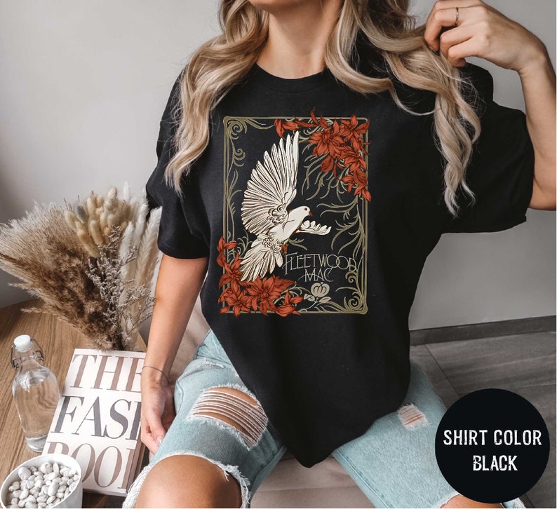 a woman wearing a black t - shirt with a picture of a bird on it