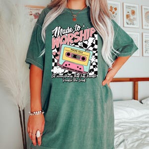 Puede incluir: Camiseta verde con un gr&aacute;fico de casete retro y el texto "Made to Worship" con el vers&iacute;culo b&iacute;blico "Salmos 150:6" y la frase "Que todo lo que tiene aliento alabe al Se&ntilde;or".