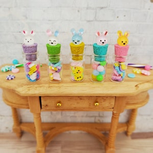 May include: Five small glass jars with cork tops decorated with colorful bunny rabbit figurines. Each jar is filled with colorful candies and small toys.