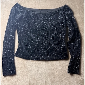 May include: A black long-sleeve top with an off-the-shoulder neckline, crafted from a velvet-like fabric featuring a dense pattern of small, shimmering silver dots distributed across the entire surface of the garment.