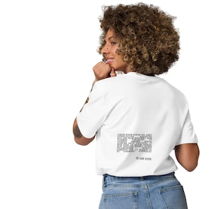Puede incluir: Camiseta blanca con un estampado gráfico negro en forma de nube de palabras que dice "You know nothing" en la espalda. La camiseta la lleva puesta una persona con el pelo rizado.
