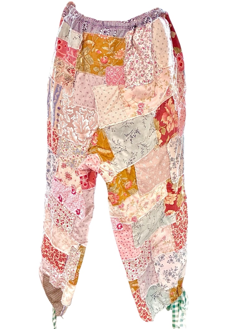May include: Patchwork trousers in a variety of floral and patterned fabrics. The trousers feature a mix of pinks, reds, yellows, and greens, with an elasticated waistband and gathered ankles. The design is a mix of vintage and bohemian styles.