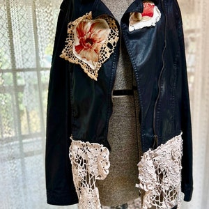 May include: A black leather jacket with lace trim and floral embellishments. The jacket has a zipper closure and a stand-up collar.