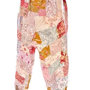May include: Patchwork trousers in a variety of floral and patterned fabrics. The trousers feature a mix of pinks, reds, yellows, and greens, with a drawstring waist and gathered ankles. The patchwork design creates a unique, bohemian style.